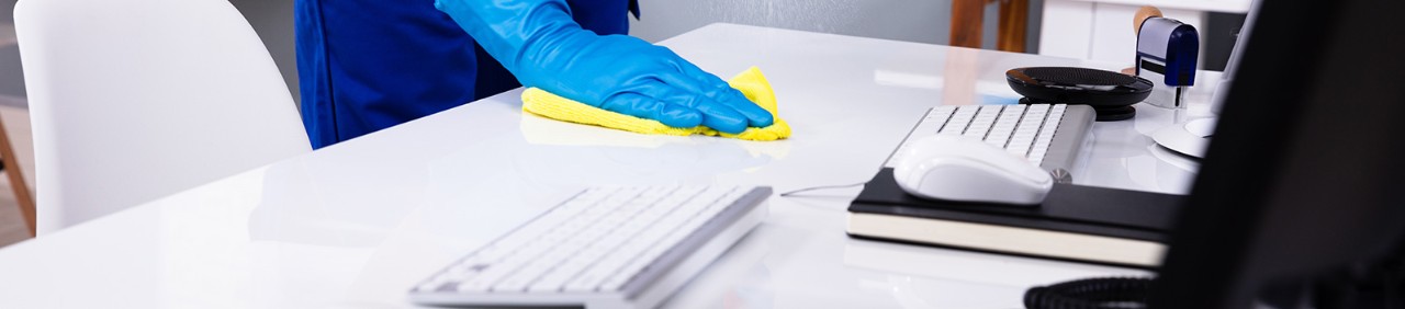 Janitor cleaning white desk in office